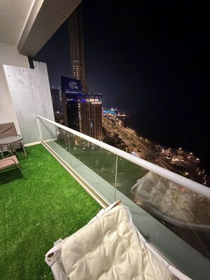A balcony with a glass railing overlooking a cityscape at night.
