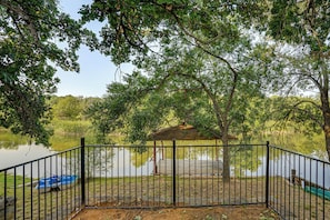 A fenced outdoor area with a wooden structure, a dock, and a body of water. - Boat Dock & Ramp! Brazos River Couple’s Retreat (Granbury)