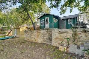 A stone wall with a metal gate leading to a green building with a white door. - Boat Dock & Ramp! Brazos River Couple’s Retreat (Granbury)