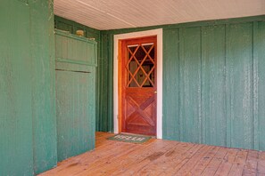 Quarto com piso de madeira, porta verde com padrão de losangos e teto branco.