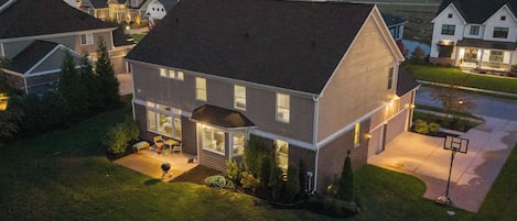 A two-story residential building with a large front porch and a basketball court.