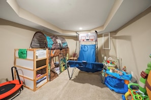 Ein Kinderzimmer mit einem Etagenbett, einem kleinen Basketballkorb und verschiedenen Spielzeugen.