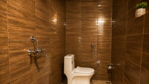 Un baño con inodoro, ducha y una planta en la pared.