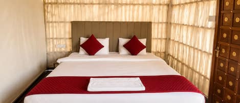 A hotel room with a large bed, a wooden headboard, and a wooden door with a floral pattern.