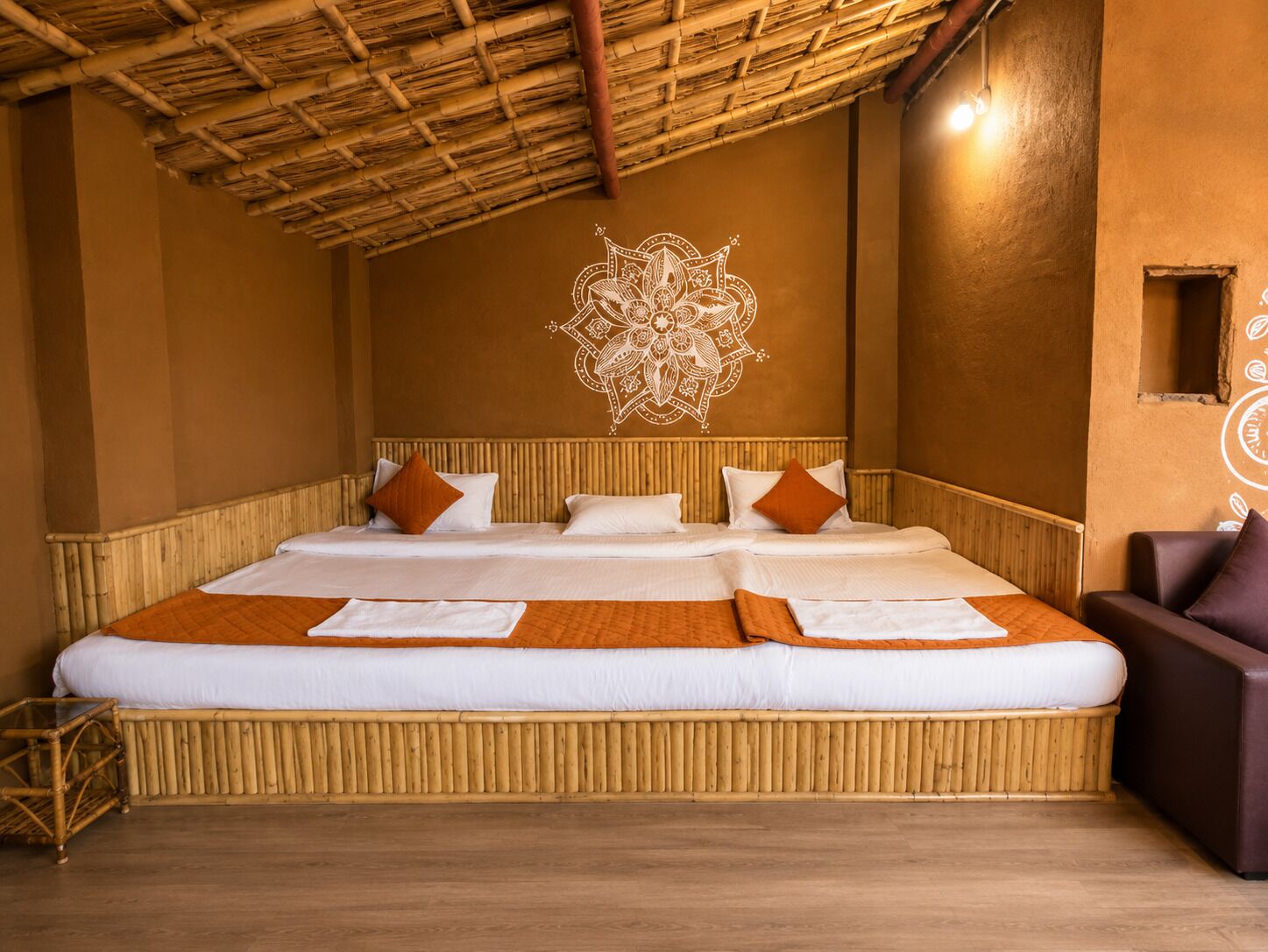 A large bed with a bamboo headboard, white bedding, and orange throw pillows.
