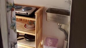 Una cocina con un lavabo, una estufa y una repisa con vajilla.