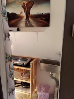 Een keuken met een spoelbak, een fornuis en een plank met servies.