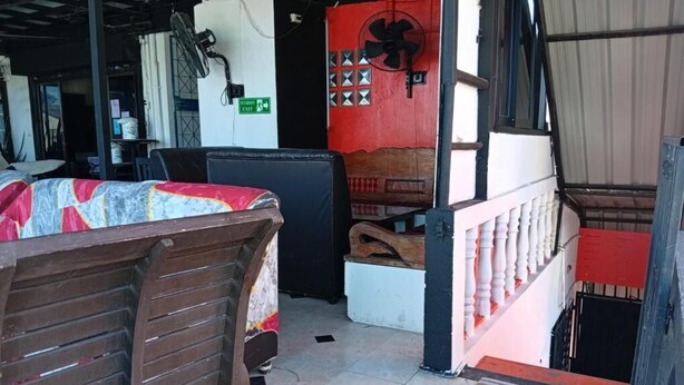Una habitación con una cama, un ventilador, una pared roja y una escalera.