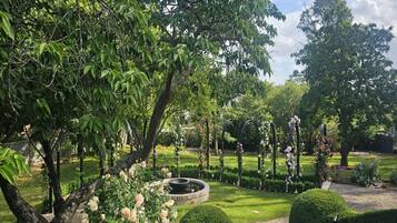 A well-maintained garden with a circular water feature, neatly trimmed hedges, and flowering plants.
