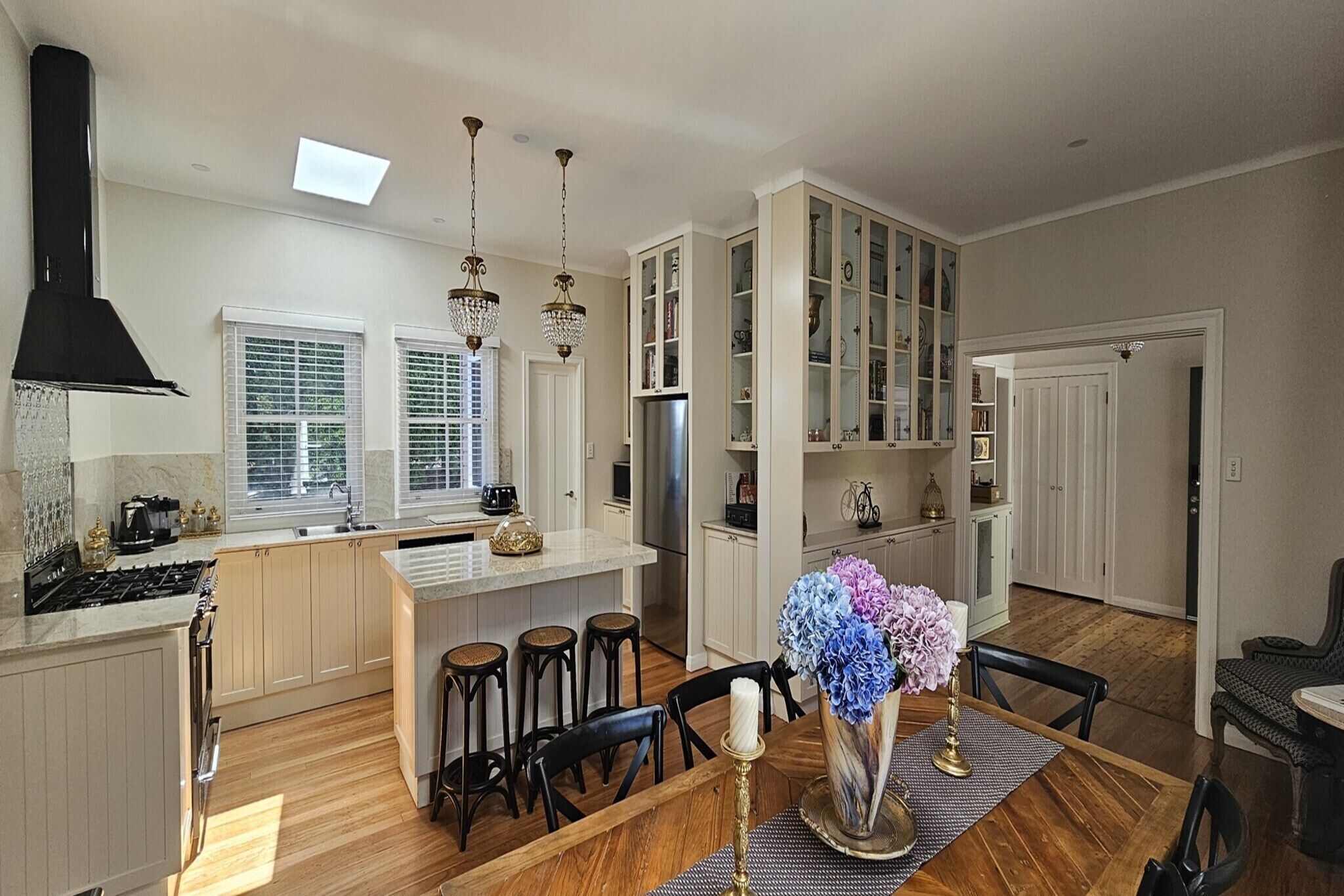 A spacious kitchen with a central island, wooden flooring, and a dining area with a table set for four.