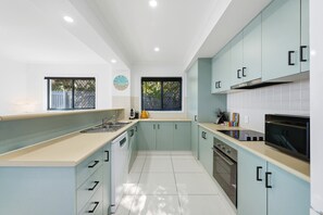 Una cucina moderna con mobili azzurri, un lavello in acciaio inossidabile e un forno nero.