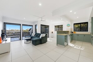 A modern apartment with a balcony, a kitchenette, and a living area with a sofa and coffee table. - Poolside 2-Bed Apartment Near Coolangatta (Coolangatta)