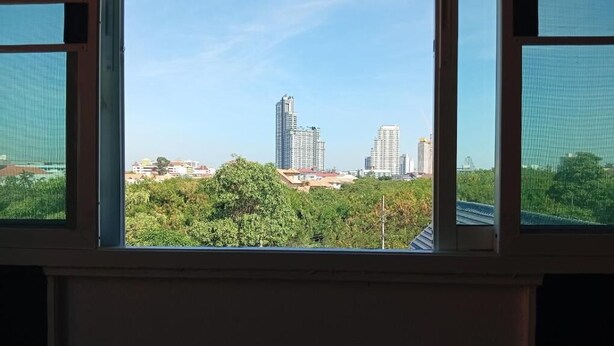 Blick aus dem Fenster auf eine Stadtansicht mit hohen Gebäuden und Grünflächen.