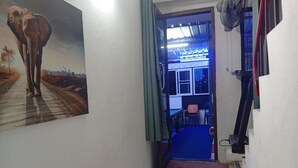Ein Flur mit Fußmatte, einem Elefantenbild und Blick in einen Raum mit blauem Teppich.