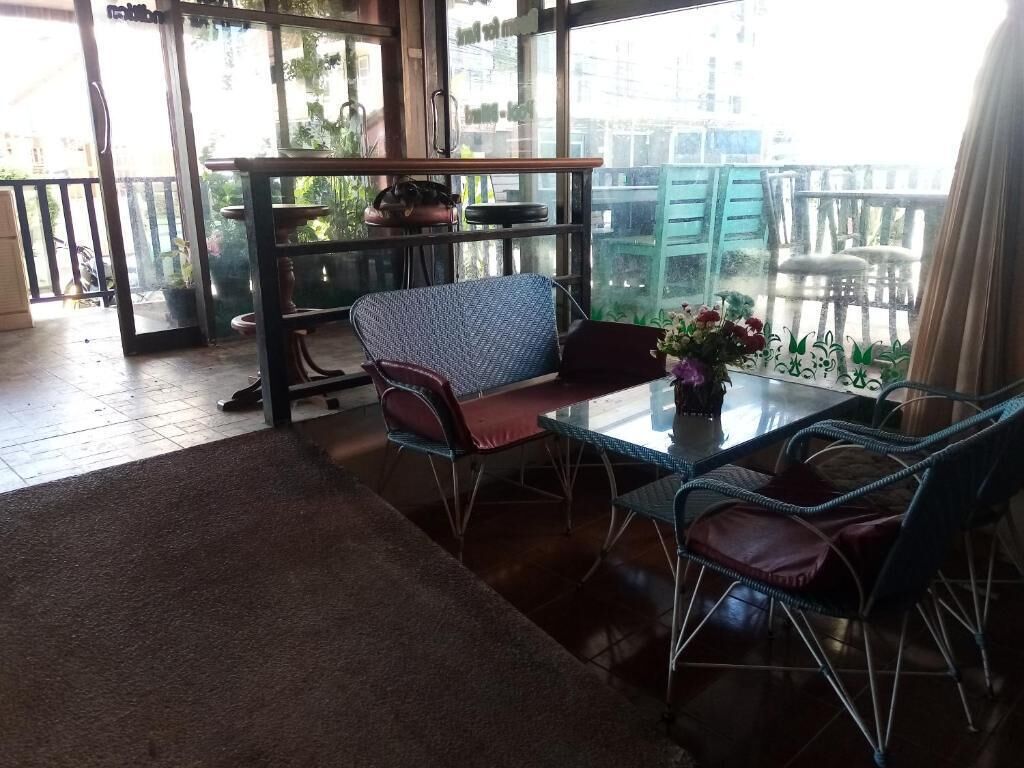 Una habitación con puerta de cristal que da a un balcón, un sofá, una mesa con sillas y una planta en maceta.