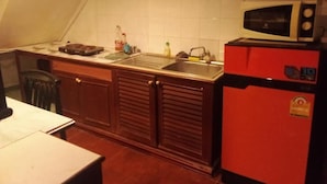 Uma cozinha com micro-ondas, geladeira vermelha e pia.