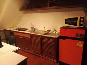 Keittiössä on mikroaaltouuni, punainen jääkaappi ja pesuallas.