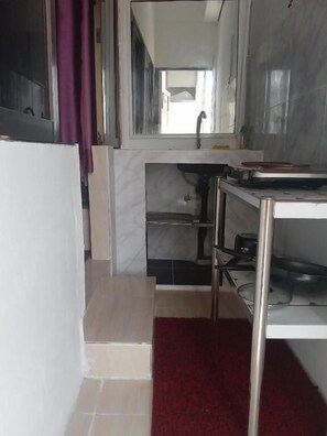 A compact kitchen with a sink, a countertop, and a small step leading to a lower cabinet. - Charming Triple Studio Room in South Pattaya (Muang Pattaya)