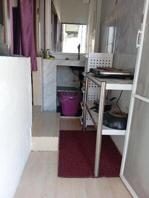 A narrow kitchen with a built-in microwave, a small sink, and a shelf with various items. - Charming Triple Studio Room in South Pattaya (Muang Pattaya)