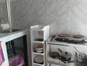 A kitchen with a marble backsplash, a white sink, and a stove with pots and pans. - Charming Triple Studio Room in South Pattaya (Muang Pattaya)