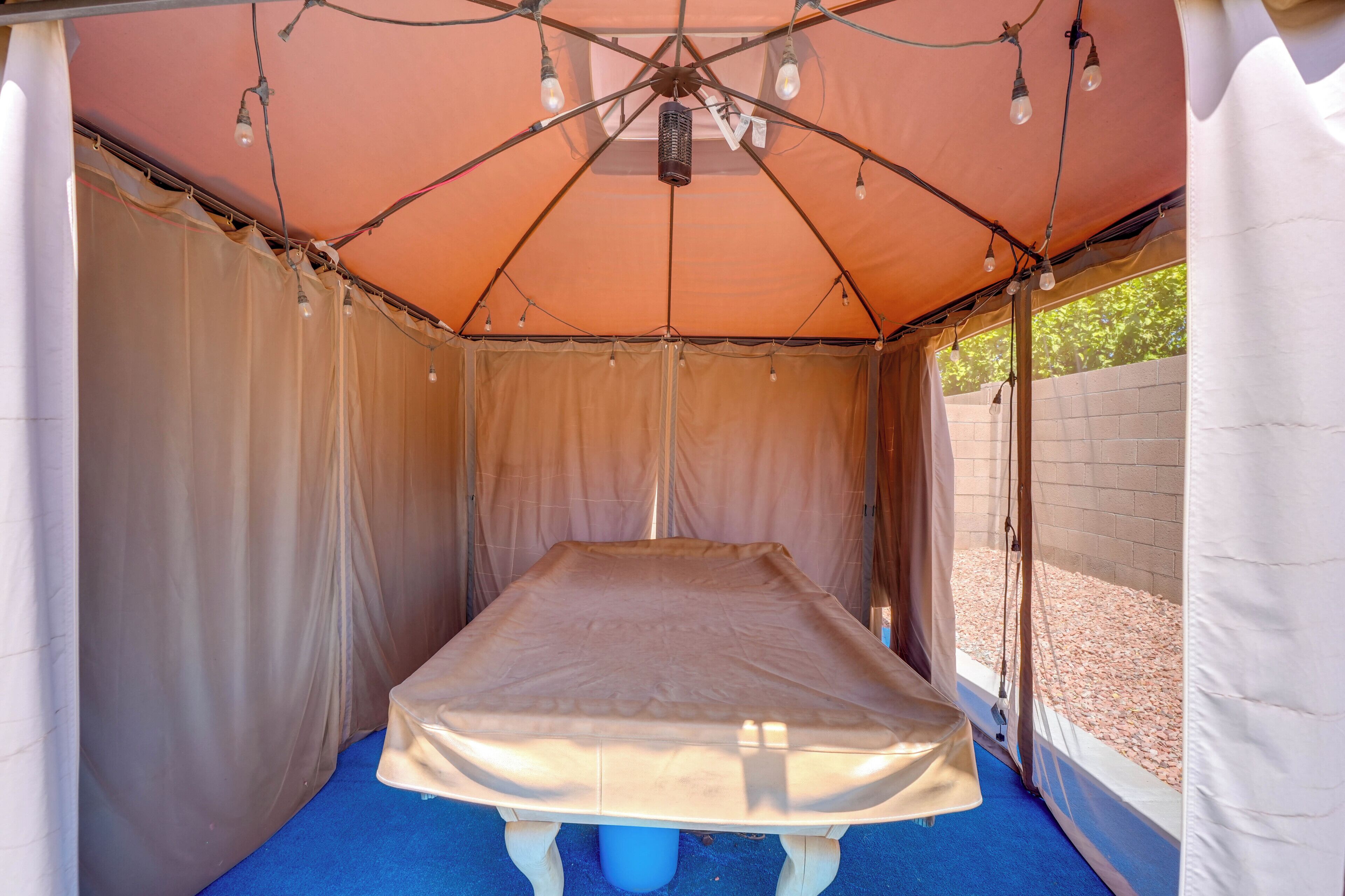 A tent with a bed, draped curtains, and string lights.