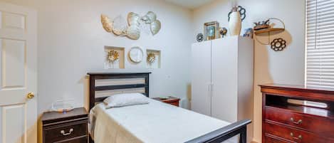 A bedroom with a bed, a dresser, a nightstand, a wall clock, and decorative wall art.