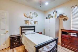 A bedroom with a bed, a dresser, a nightstand, a wall clock, and decorative wall art. - Backyard Billiards & BBQ! Surprise Desert Stay (Surprise)
