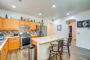 A modern kitchen with wooden cabinets, a stainless steel refrigerator, and a built-in oven. - Backyard Billiards & BBQ! Surprise Desert Stay (Surprise)