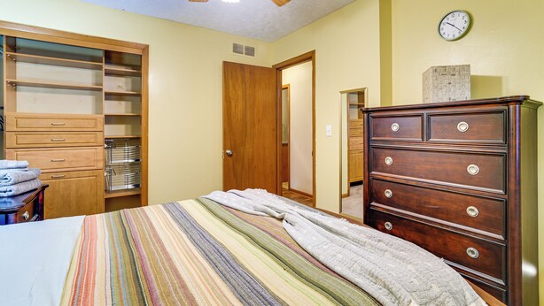 Un dormitorio con una cama, un aparador, un armario y un reloj en la pared.