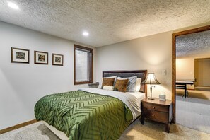 Ein Schlafzimmer mit einem Bett, einem Nachttisch, einer Lampe und drei gerahmten Bildern an der Wand.