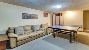 Una habitación con un sofá, una mesa de ping pong y un cuadro de un paisaje urbano.