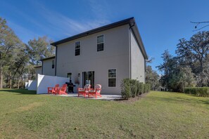 A modern two-story house with a patio area featuring red chairs and a barbecue grill. - Twin Ocala Townhomes! 1 Mi to WEC (Ocala)
