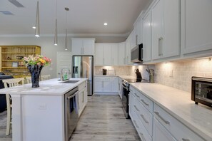 A modern kitchen with white cabinetry, a central island, stainless steel appliances, and pendant lighting. - Twin Ocala Townhomes! 1 Mi to WEC (Ocala)