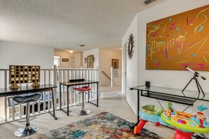 Ein Zimmer mit Esstisch, einem roten Stuhl, einem Glastisch, einem farbenfrohen Teppich und einem Spielzeug für Kinder.