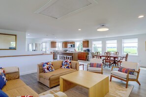 A spacious living area with a sofa, chairs, a coffee table, and a kitchen in the background. - 1 Mi to Plum Island Beach with Beautiful Views (Newbury)