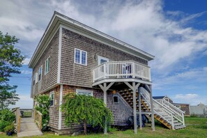 A two-story house with a wooden exterior, a covered porch, and a staircase leading to the second floor. - 1 Mi to Plum Island Beach with Beautiful Views (Newbury)