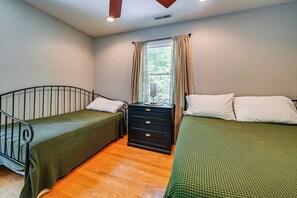 Una habitación con dos camas individuales, un aparador y una ventana con cortinas.