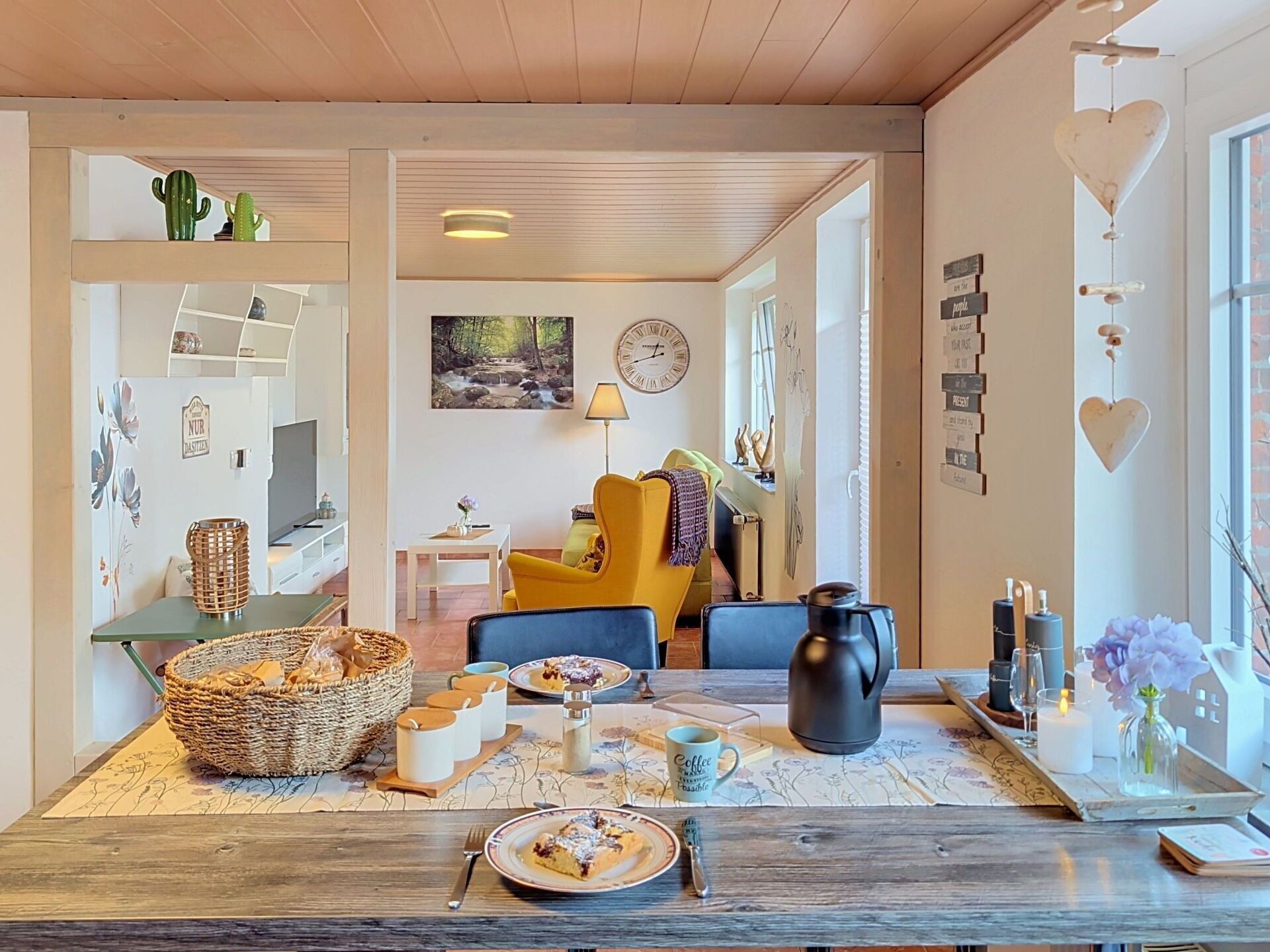 A cozy dining area with a wooden table set for two, a yellow chair, and a clock on the wall.