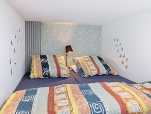 Ein Schlafzimmer mit Bett, Kissen, einer Lampe und Schmetterlingsstickern an der Wand.