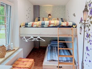 Ein kleines Zimmer mit Etagenbett, einem Tisch mit Korb und einem Heizkörper.