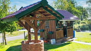 Ein rustikales Holzgebäude mit geneigtem Dach, einem Backsteinsockel und einer kleinen Veranda.