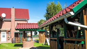 Ein rustikaler Außenbereich mit Holzzaun, Backstein-Pflanzgefäß und einer roten Ziegeldachkonstruktion.