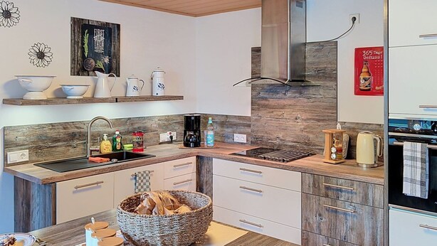 Eine moderne Küche mit einer zentralen Kochinsel, Holzschränken und einem eingebauten Backofen.