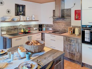 A modern kitchen with a central island, wooden cabinetry, and a built-in oven. - Cosy apartment for 3 guests with WIFI, TV and terrace (Bremerhaven)