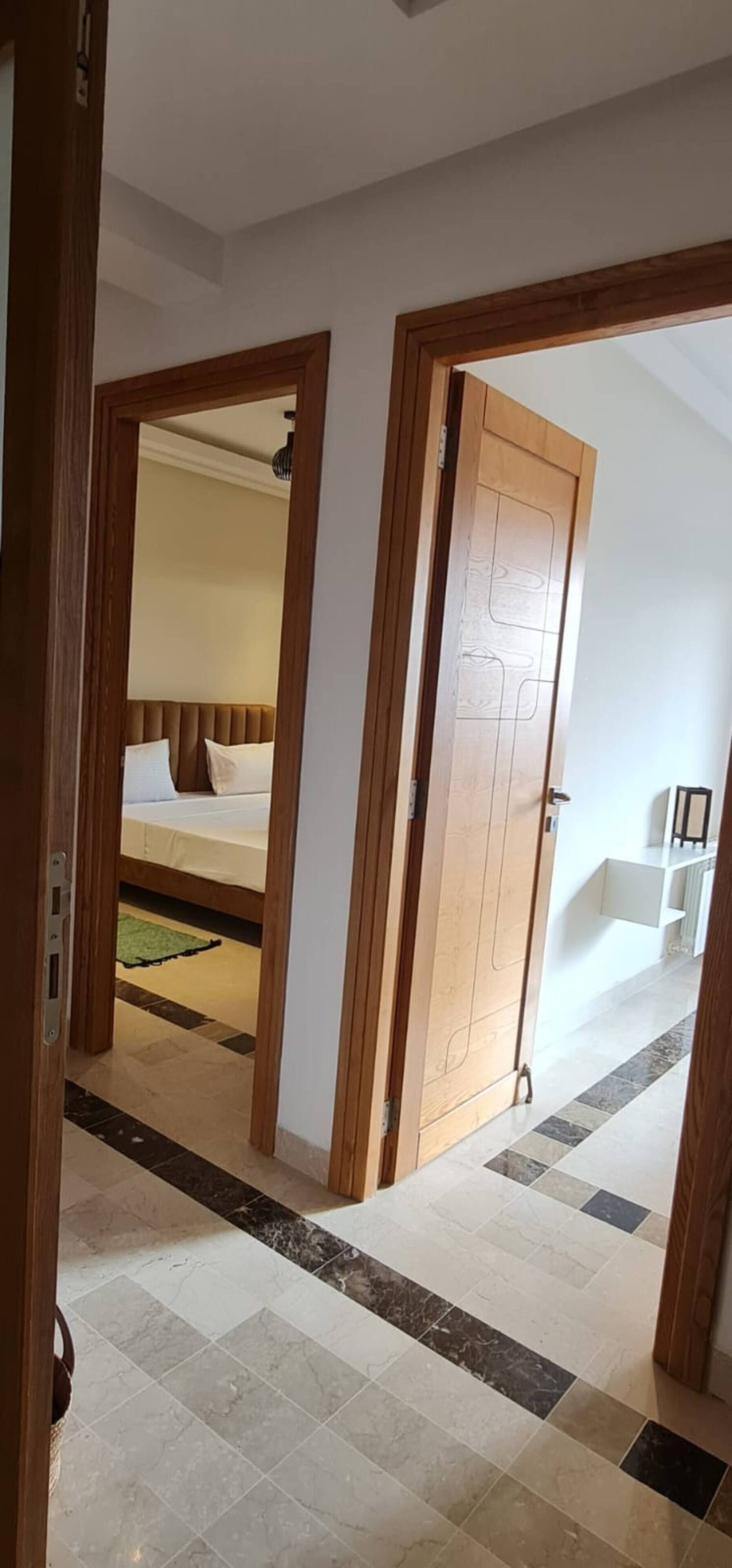A hotel room with a bed, a wooden door, and a tiled floor.