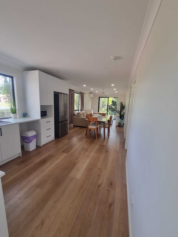 A modern kitchen with white cabinets, a built-in fridge, and a dining area with a table and chairs.
