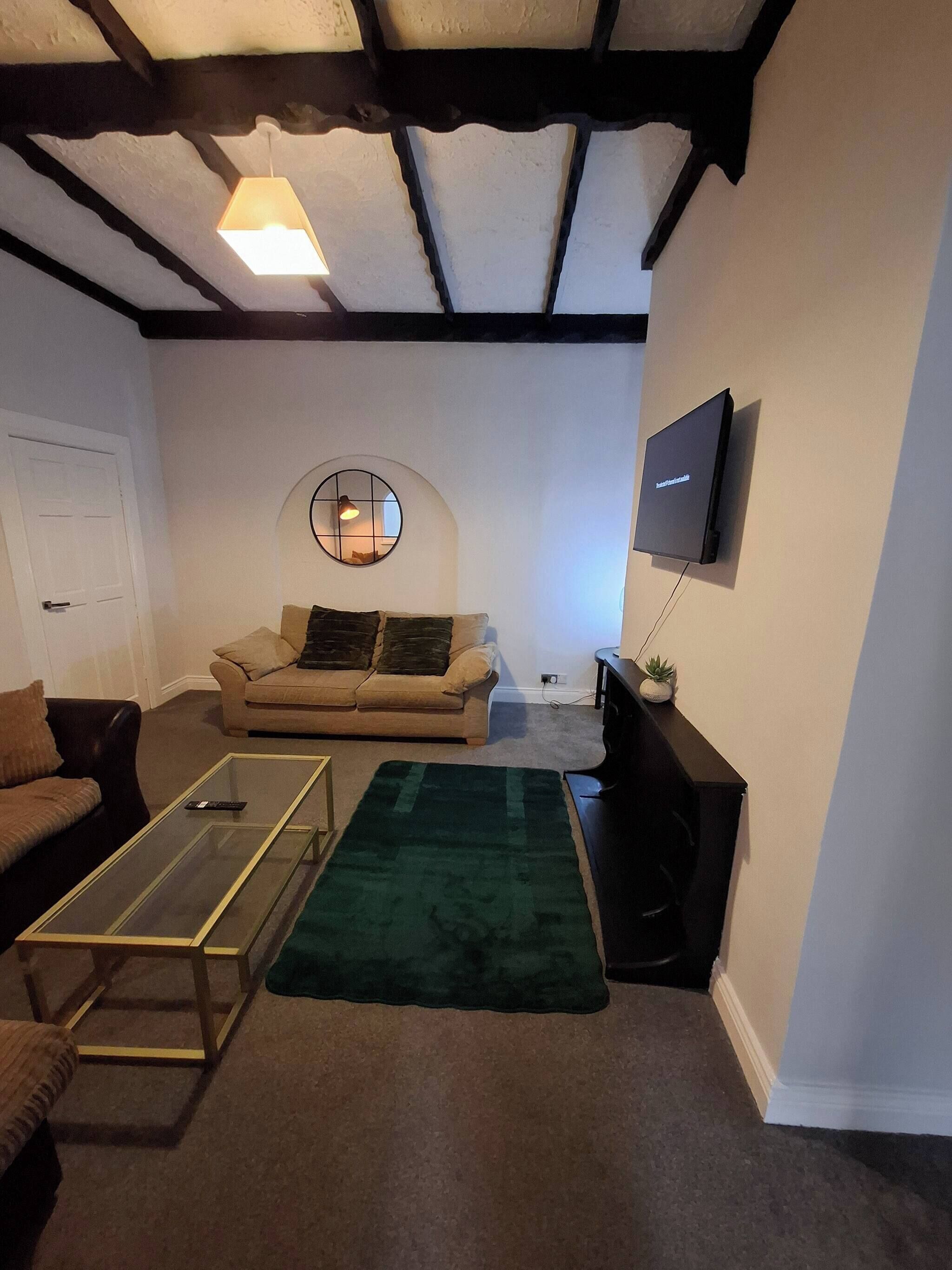 Een woonkamer met een bank, een salontafel, een televisie en een decoratieve spiegel.