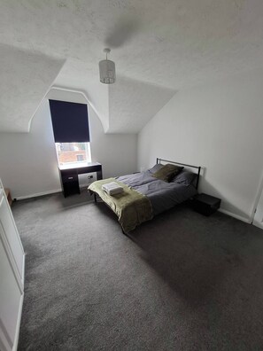Ein Schlafzimmer mit Bett, Schreibtisch und Fenster.