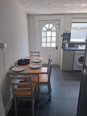 Eine kleine Küche mit Essbereich, einer Waschmaschine und einem Fenster mit Jalousien.