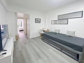 Un dormitorio moderno con cama, televisión, escritorio y silla.